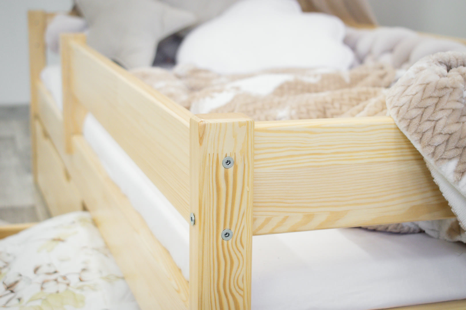 zbliżenie na zaokrągloną krawędź barierki łóżka dziecięcego z drewna sosnowego